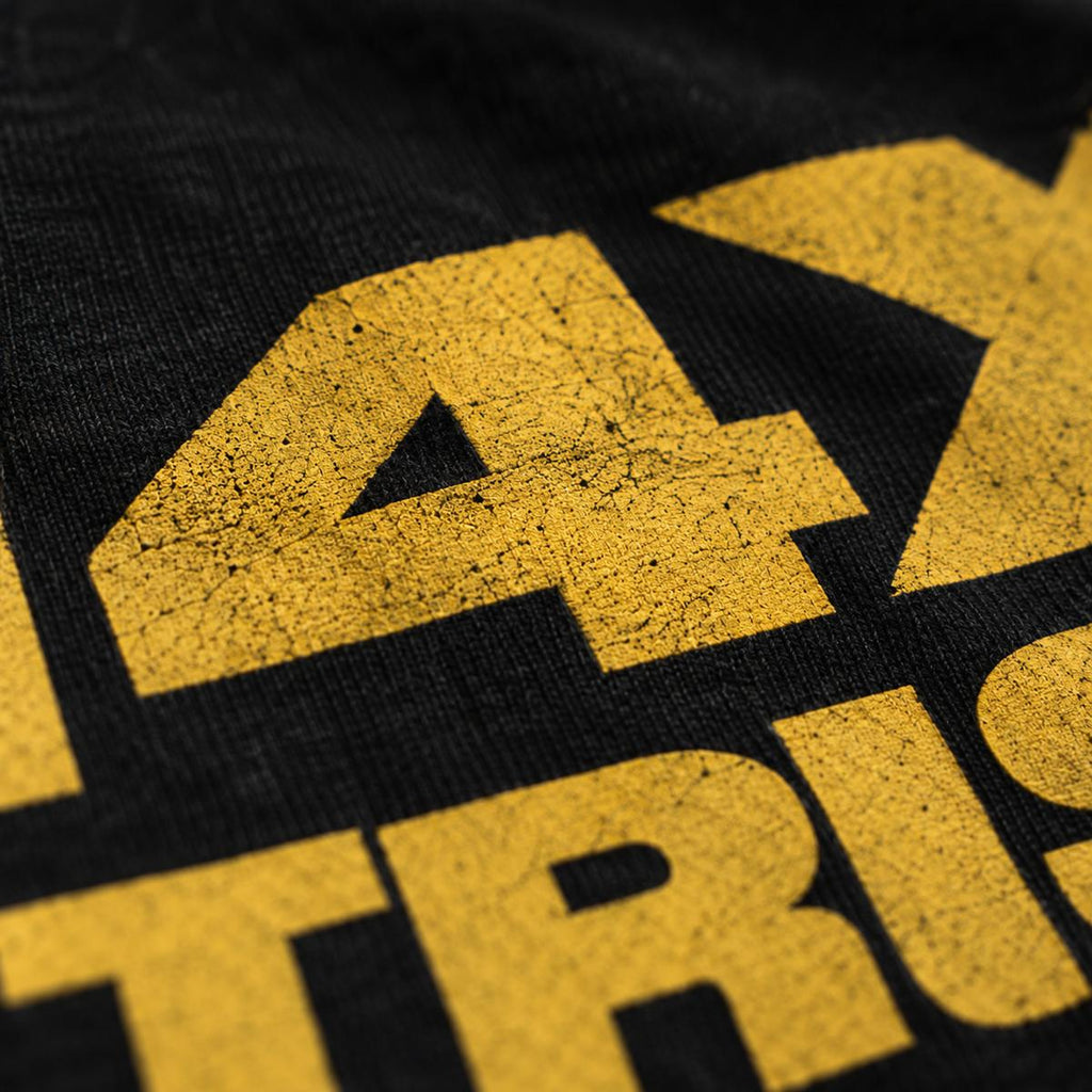 Siebdruck des In 4X We Trust Tee in Nahaufnahme, gelbe Schrift auf schwarzer Baumwolle
